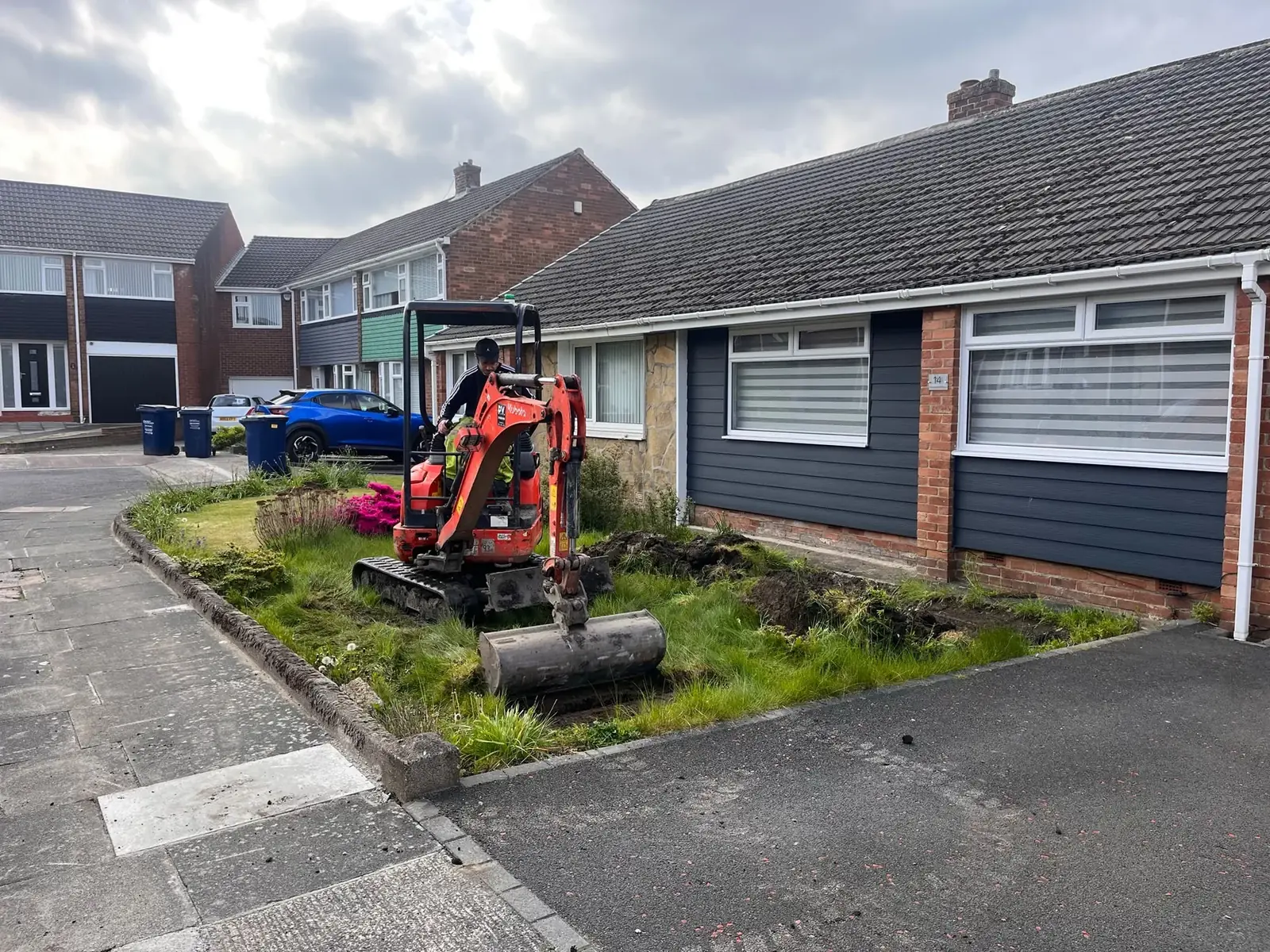 Mini excavator digging out the front garden of a bungalow before a new driveway in the North East