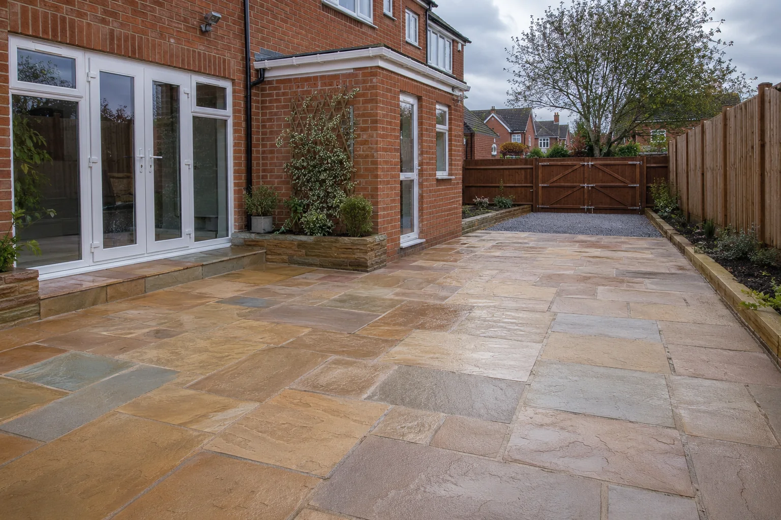 Indian sandstone patio with mixed warm tones beside a brick house in Newcastle